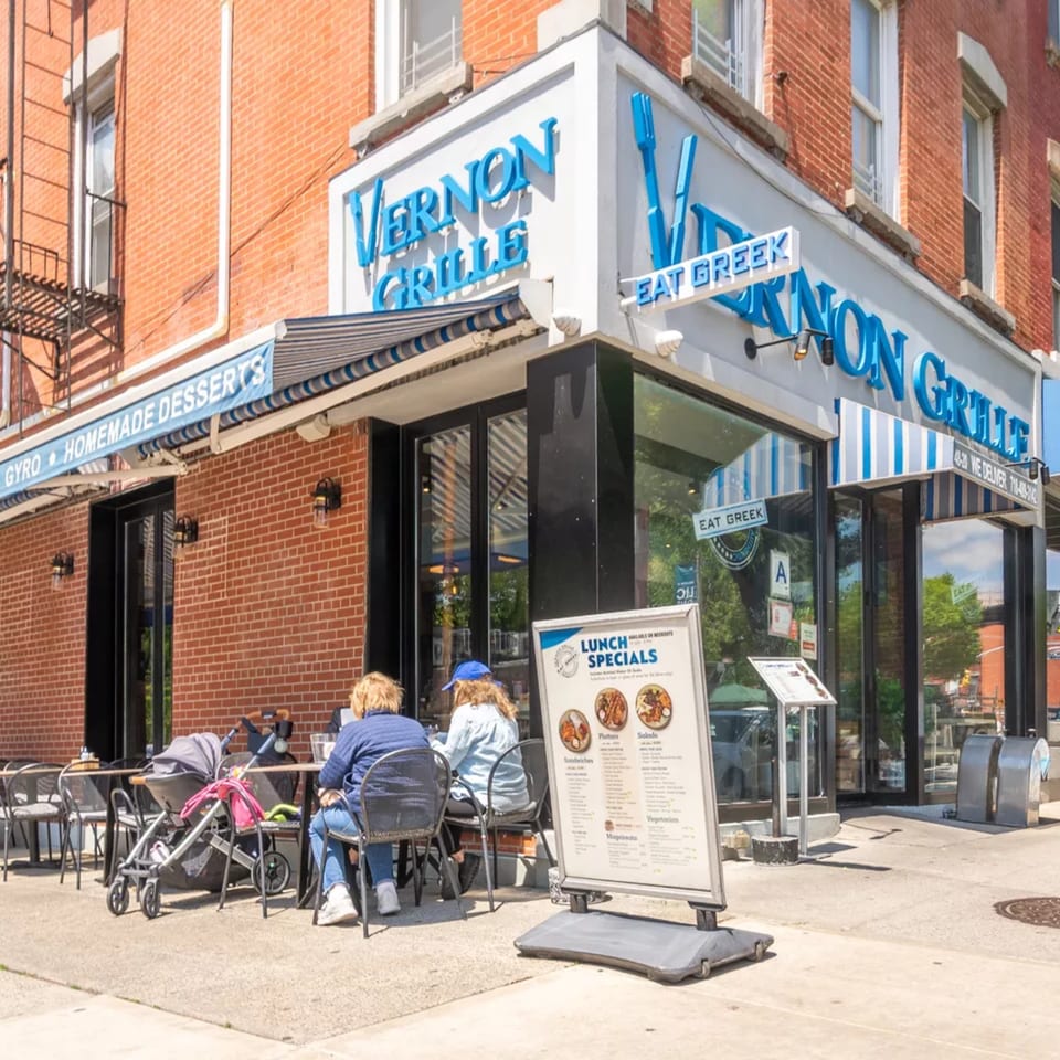 Vernon Grille restaurant exterior with two people dining outdoors and a lunch specials sign.